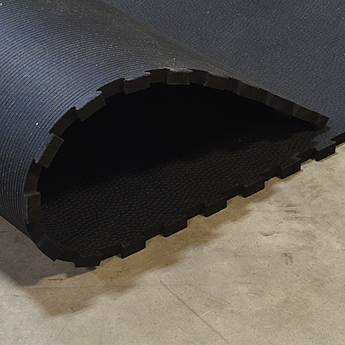 interlocking rubber stall mat on concrete curled up to show bottom of mat