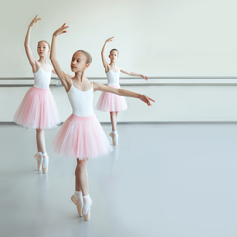 Three kid ballerinas on gray marley dance floor