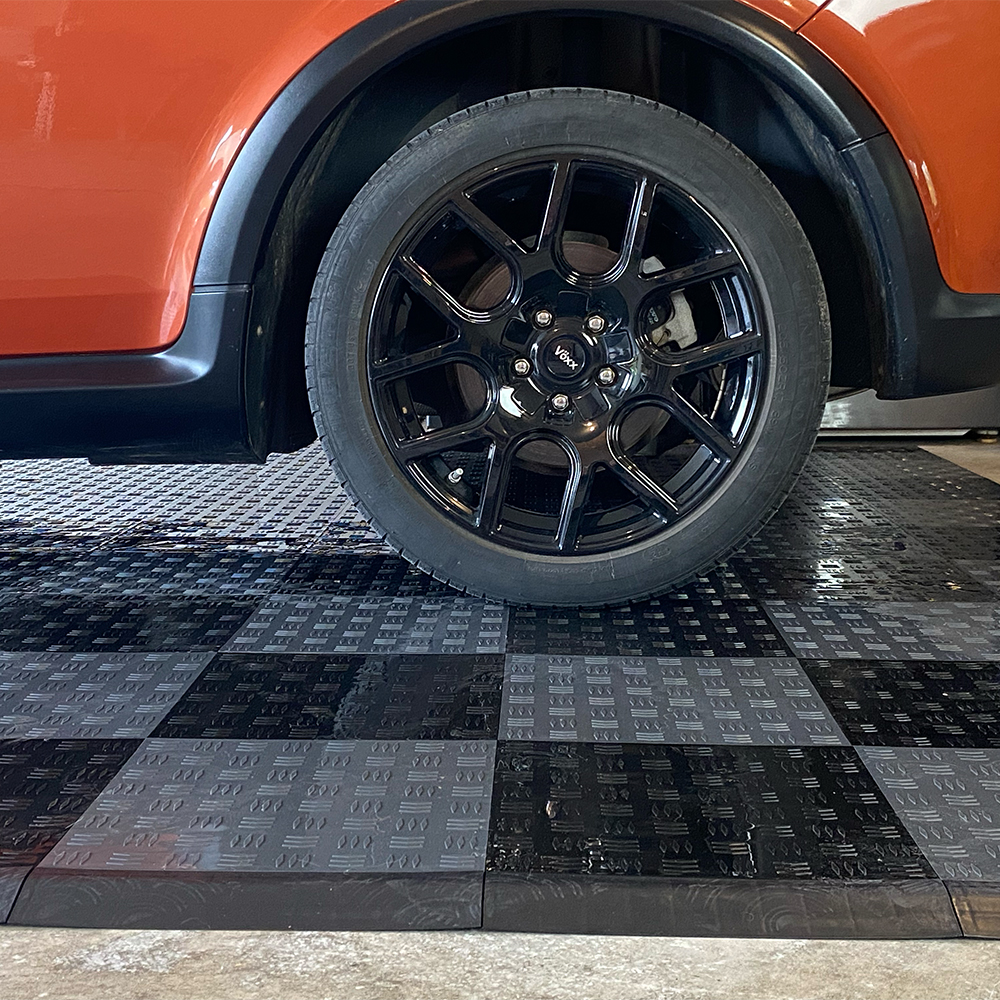 raised garage tiles gray and black pattern and back wheel of car