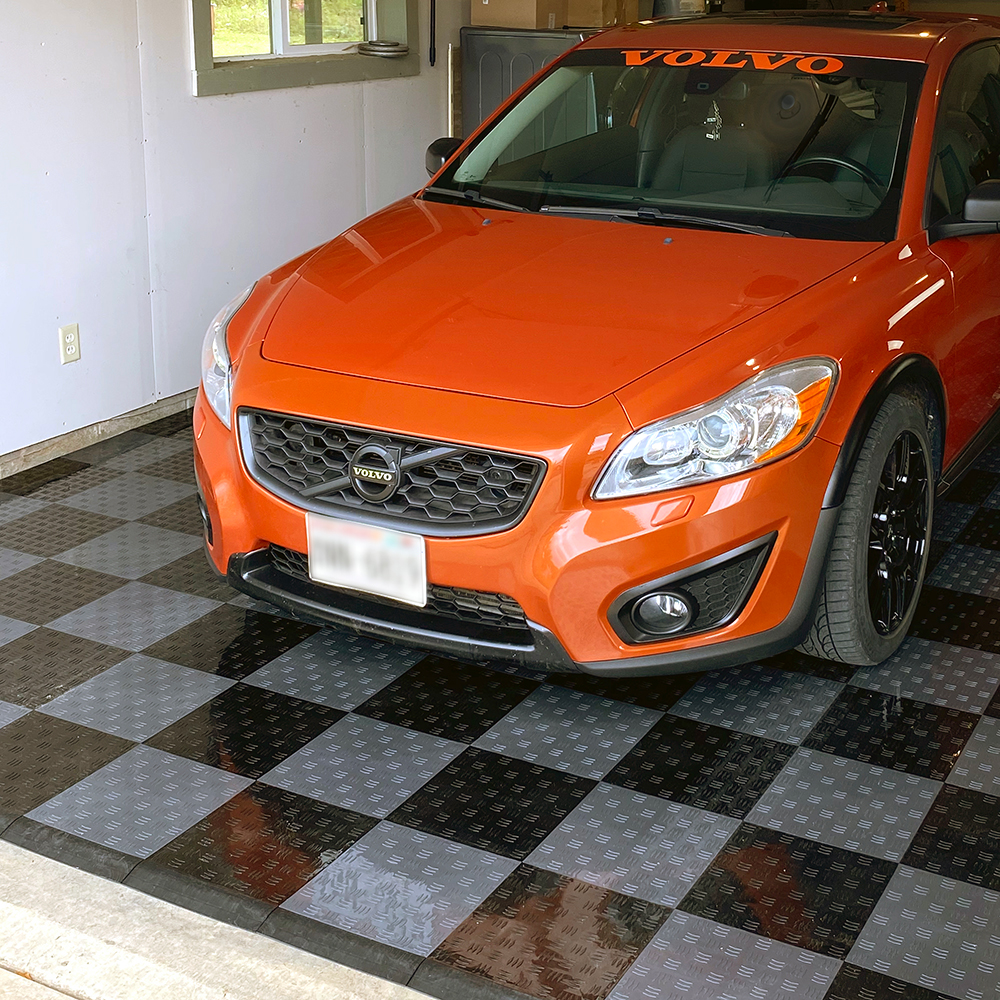 orange volvo car in garage with gray and black floor tiles