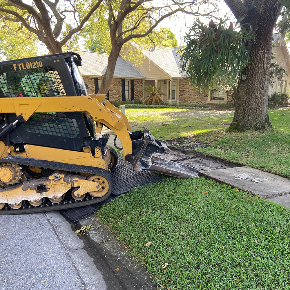 Skid steer on curb using landscape mat to protect grass Gmats 