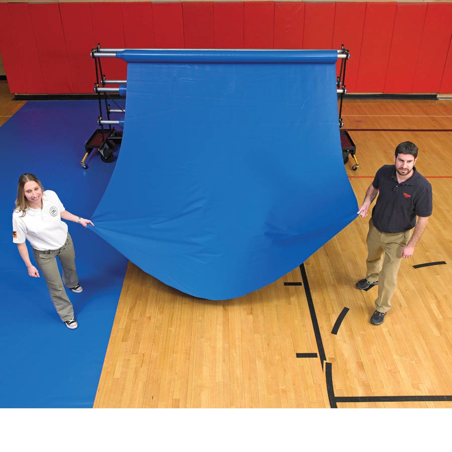 people unrolling vinyl gym floor cover off of safety storage rack