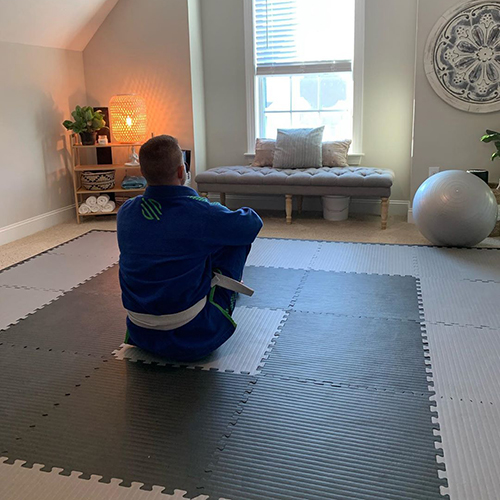 man sitting on bjj jiu jitsu grappling puzzle mats in exercise room