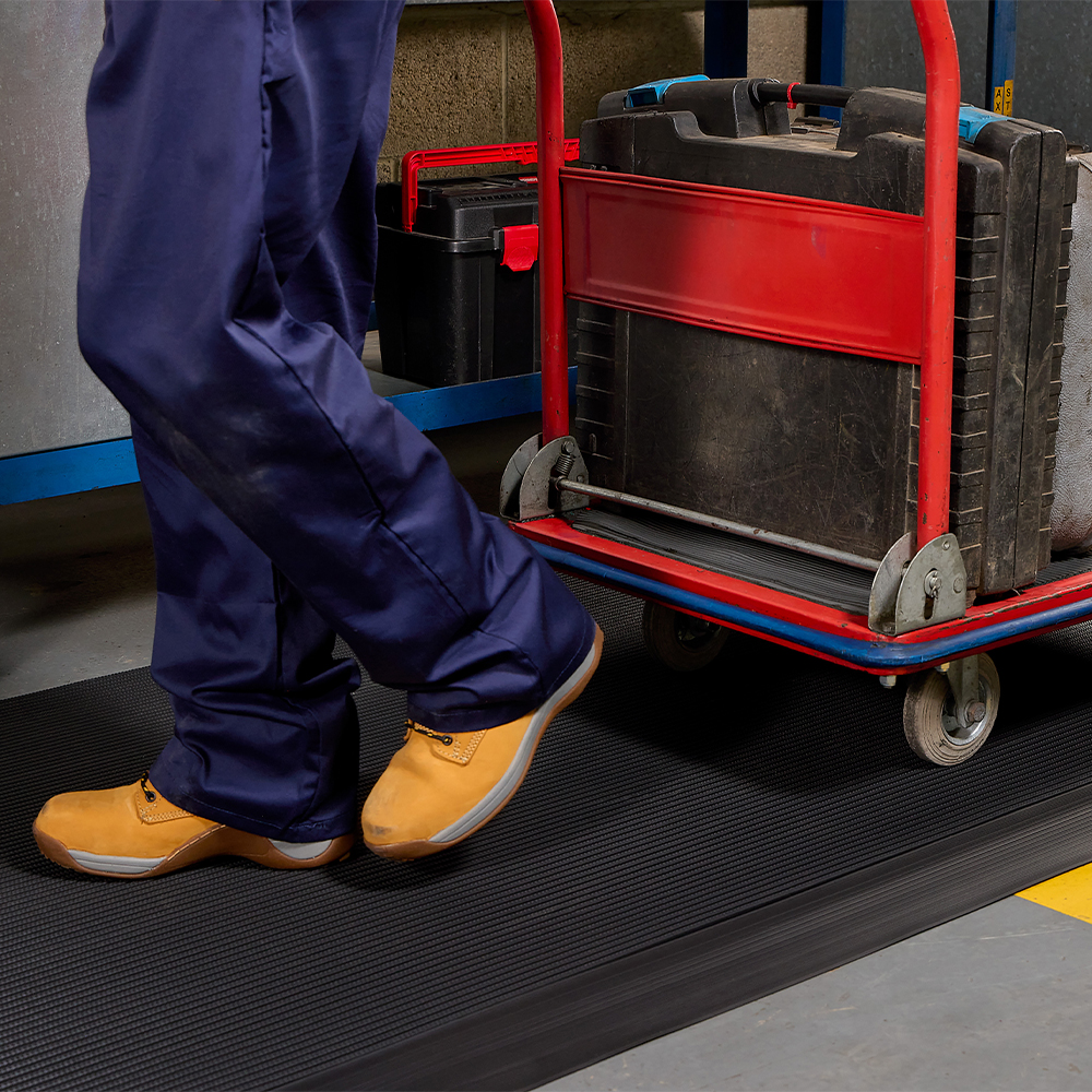 close up of person with cart walking on Firmagrip Industrial Matting in industrial facility