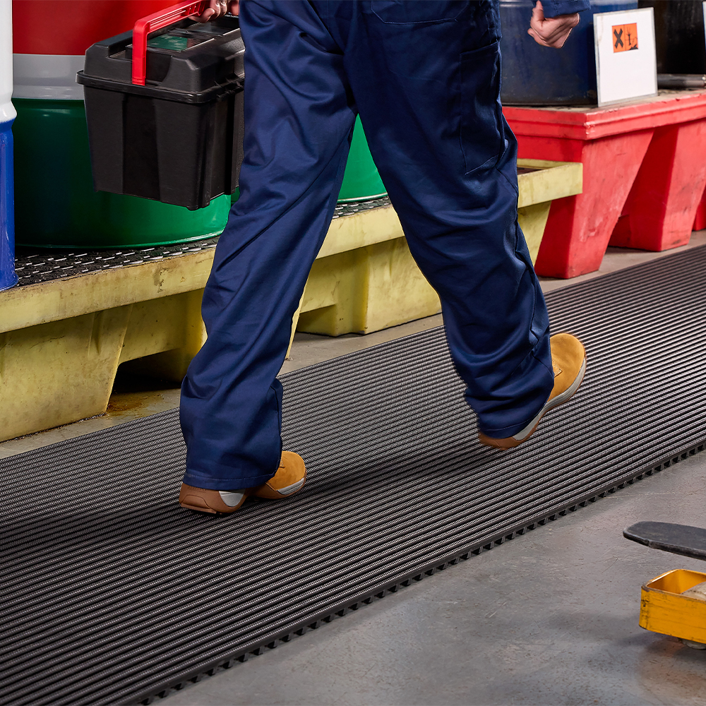 person carrying toolbox while walking on black Flexigrid Industrial Matting 2 x 16.5 ft Roll 