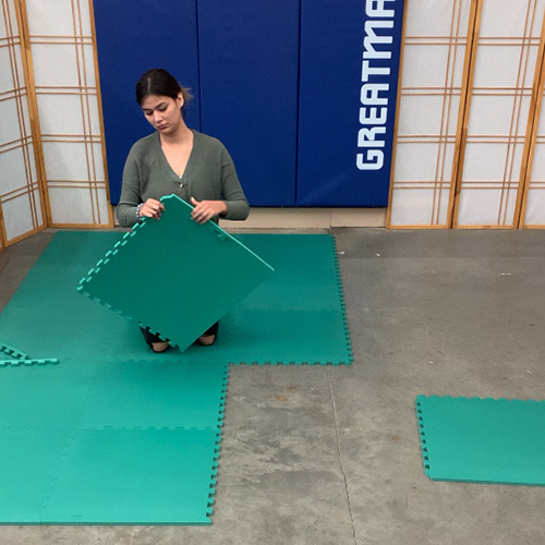 Installing green Foam Premium Interlocking Trade Show Mats 20x20 Ft. Kit