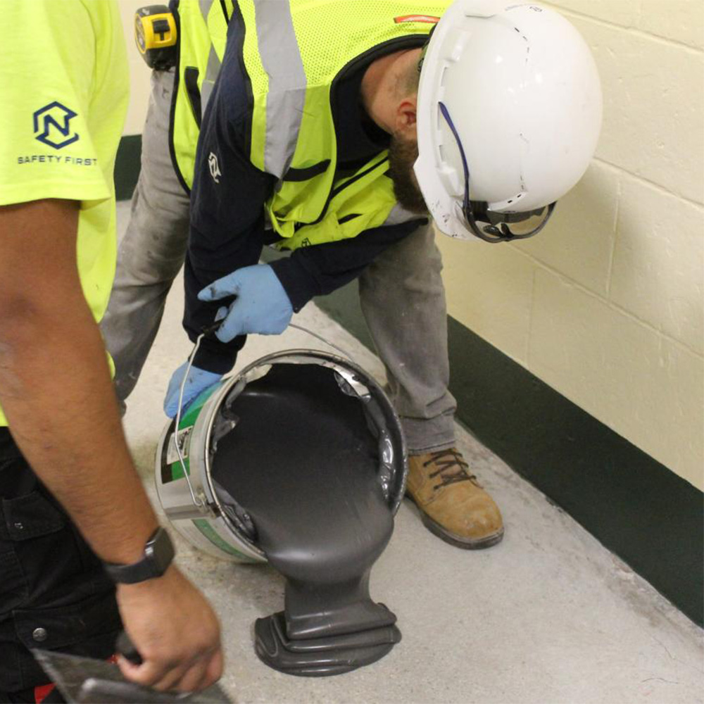 EGrip III Adhesive 4 Gal Pail being poured onto subfloor