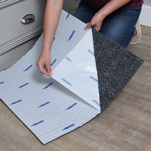 person peeling backing off peel and stick carpet tile