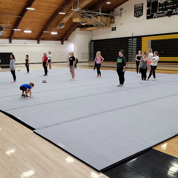 cheerleading practice on gray cheerleading mats in gymnasium