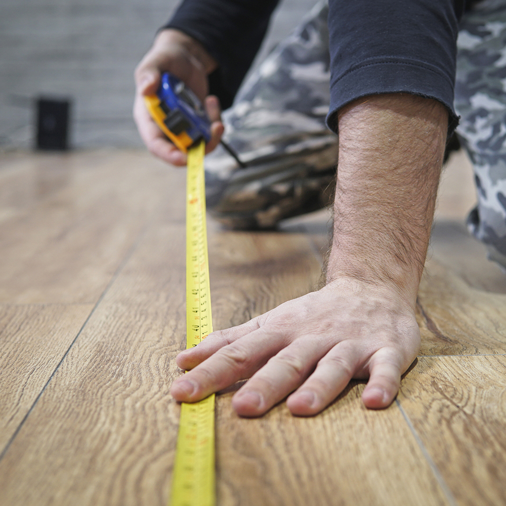 measuring the floor with tap measure to figure square footage