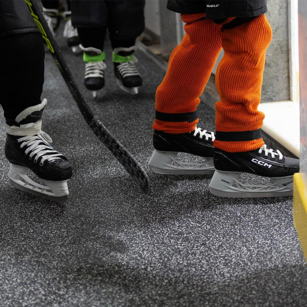 Players entering ice onto Blade Rolled Rubber 9 mm x 4 Ft. Wide Per SF in Zebra