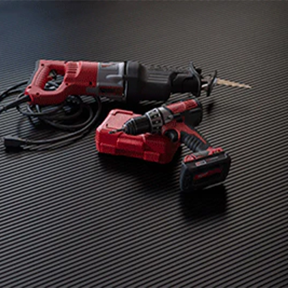 Tools laying on G-Floor Ribbed Tread Vinyl Multipurpose Roll 55 mil x 5x10 Ft. in midnight black