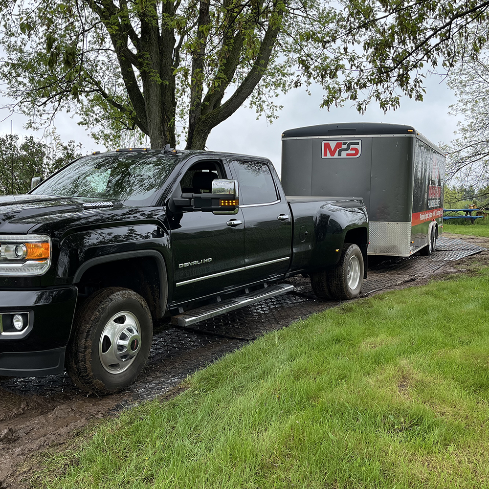 truck and trailer driving on ground protection mats in mud