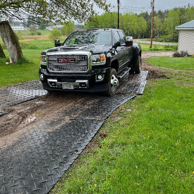 truck driving on ground protection mats in muddy driveway path