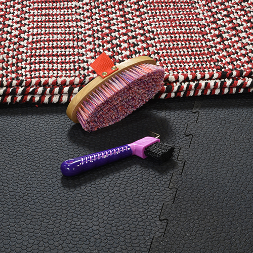 close up of interlocking rubber stall mats with horse tack on top