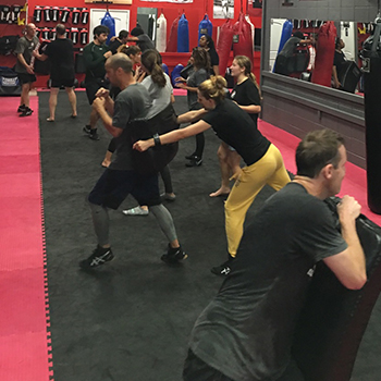 krav maga class wearing shoes on mats