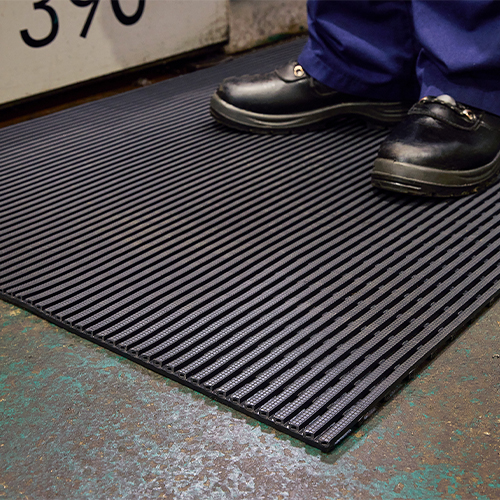 close up of person in work boots standing on heronair industrial matting on concrete