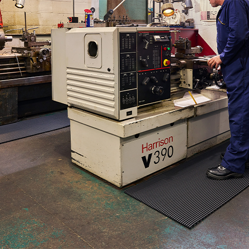 person working at machine in factory standing on heronair anti-fatigue matting