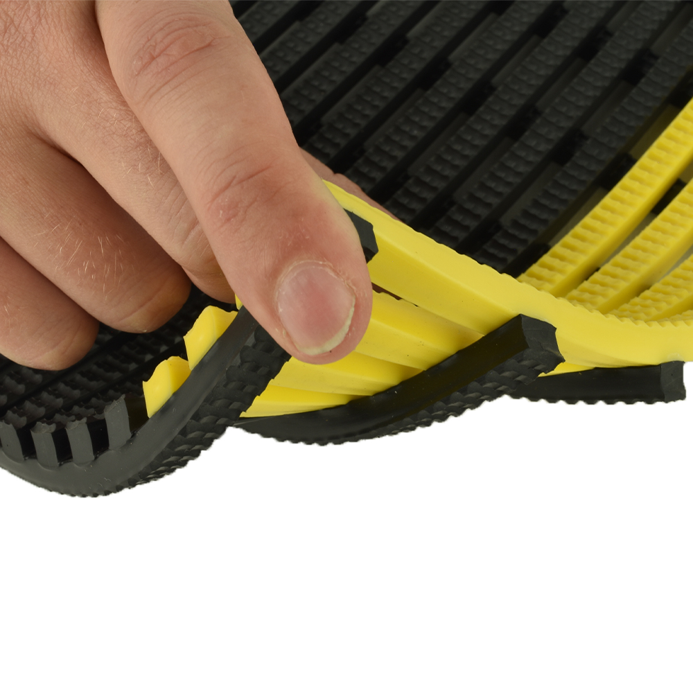 person's hand holding up a corner of vynagrip matting with yellow border