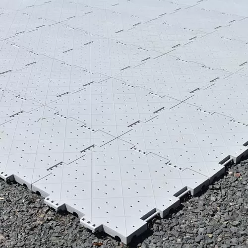 grey temporary floor tile with holes installed over gravel