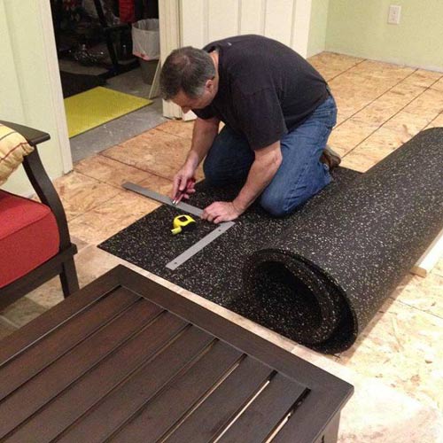 man measuring rubber flooring roll over plywood