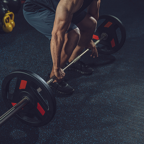 Man weightlifting with barbell on blue flecked rolled rubber flooring