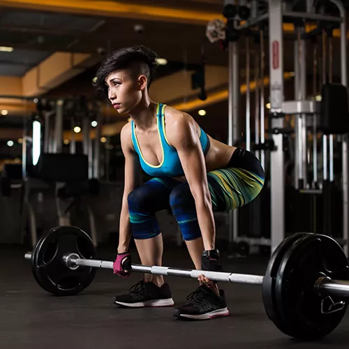 woman lifting weights in gym with rubber flooring