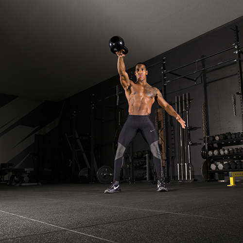 Man in weight room lifting weights on black rubber tile