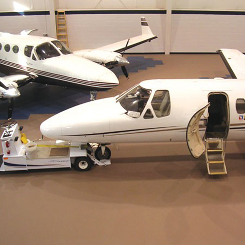 airplanes in hangar with tan flooring