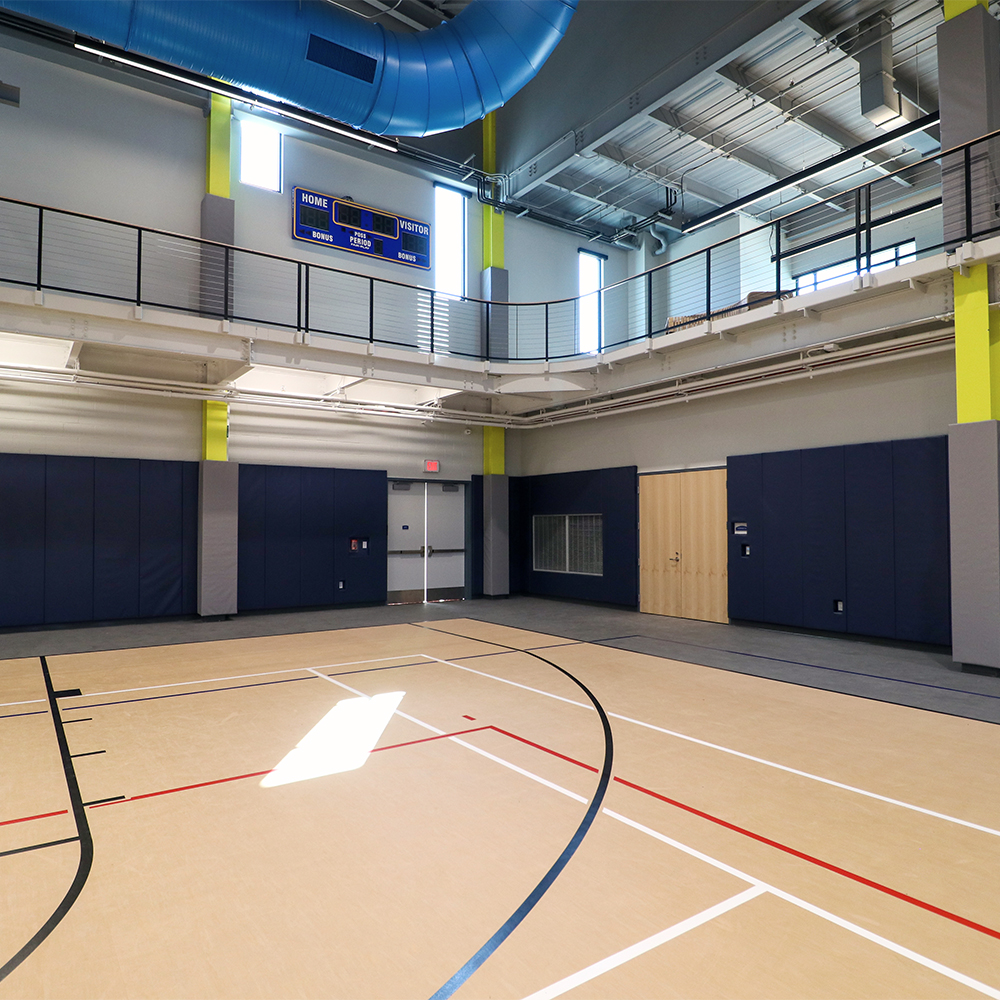 gray Safety I-Beam Pads installed in gymnasium with dark blue wall pads