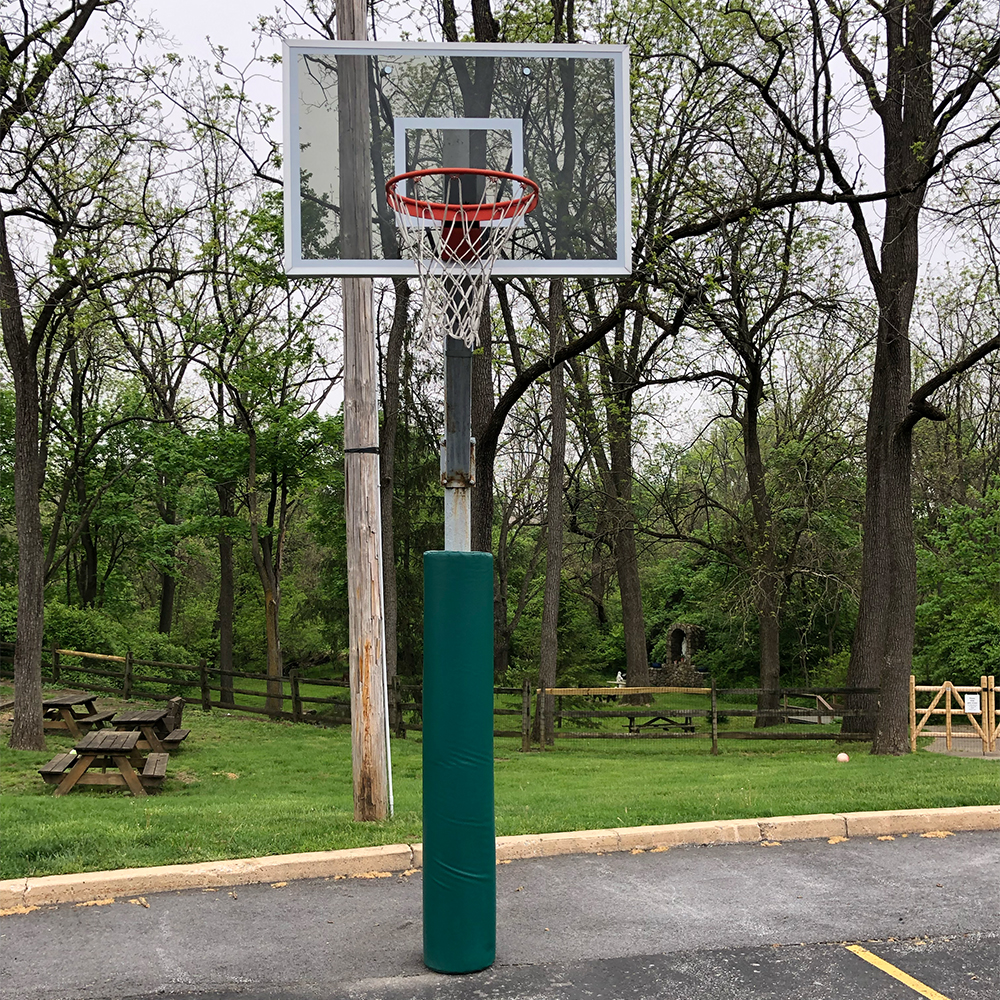 green safety pole pad on basketball hoop pole in parking lot