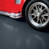 Red care with sidepipes parked on G-Floor Ribbed Tread Garage Floor Roll 55 Mil x 8.6x24 Ft. in midnight black