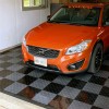 orange volvo car in garage with gray and black floor tiles
