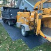 truck driving on ground protection mats over grass with tree cutter