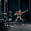 Woman doing kettlebell racked squats on black rolled rubber flooring