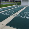 VersaCourt Outdoor Game Court Corner Reducer in green installed on shuffleboard court