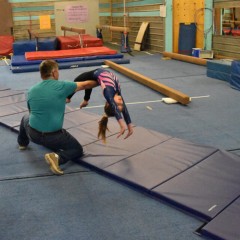 kid tumbling with spotter on gymnastics mats lined up thumbnail