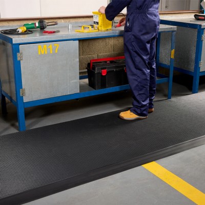 person standing at industrial workbench on Firmagrip Industrial Matting