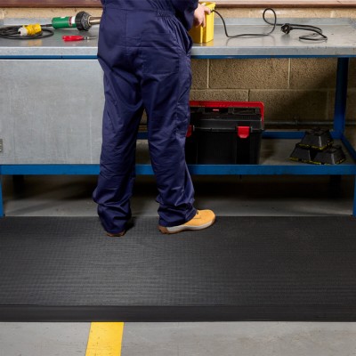 person standing at industrial workbench on Firmagrip Matting