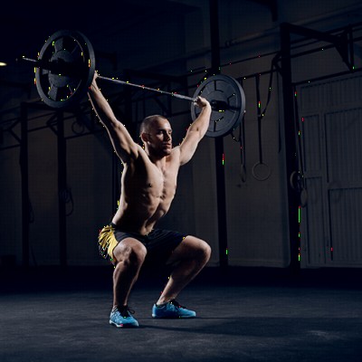 Man doing overhead squats overtop of black rolled rubber flooring